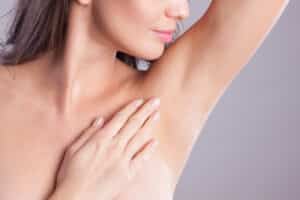 A woman showing her smooth underarms after receiving laser hair removal.