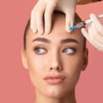 A woman receiving a BOTOX® Cosmetic injection in her forehead.