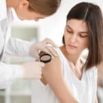 Woman having a mole on her arm looked at by her oncologist.